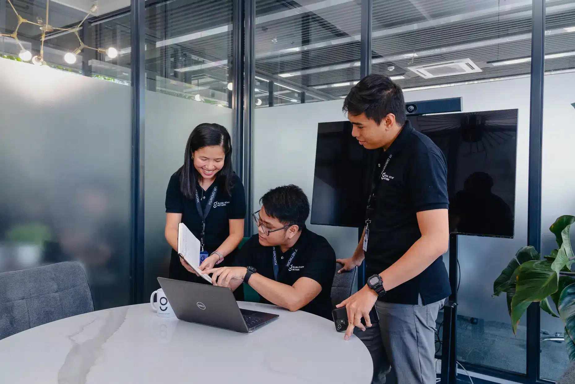 Dedicated Global Staff Network team members collaborating on computers in a modern Philippine office.